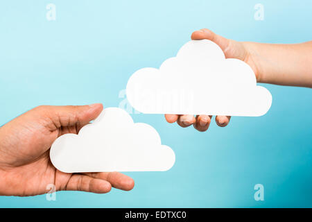 Zwei Hände halten Papier Wolken auf blauem Hintergrund. Cloud-computing-Konzept. Stockfoto