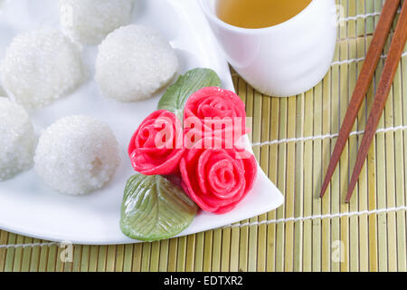 Draufsicht horizontalen abgewinkelten Bild der chinesischen süßer Klebreis Kugeln, im Hintergrund, rote Dekoration Rosen und grünen Tee mit nat Stockfoto