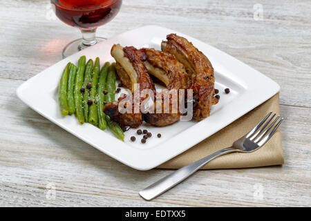 Nahaufnahme von gegrilltem Schweinefleisch Spareribs, grüne Bohnen und Rotwein zum Essen bereit Stockfoto
