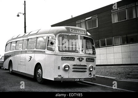 1960er Jahre historische Bild zeigt einen Midland Bluebird-Trainer auf private Vermietung parkten außerhalb eines modernen Wohnblocks wartet auf seine Fahrgäste, Schottland, UK. Stockfoto