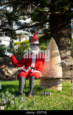 Surfer Weihnachtsmann Santa Claus Surfen Freunden Modell sitzen auf Gartenbank holding Surfbrett halten kann Bier NSW Australia Stockfoto