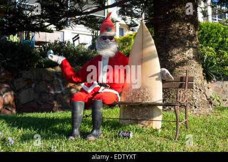 Surfer Weihnachtsmann Santa Claus Surfen Freunden Modell sitzen auf Gartenbank holding Surfbrett halten kann Bier NSW Australia Stockfoto