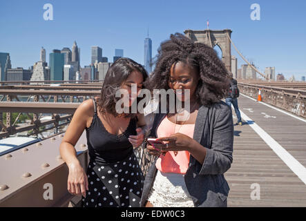 Zwei Freunde teilen sich einen Moment auf der Brooklyn Bridge in New York City. Stockfoto