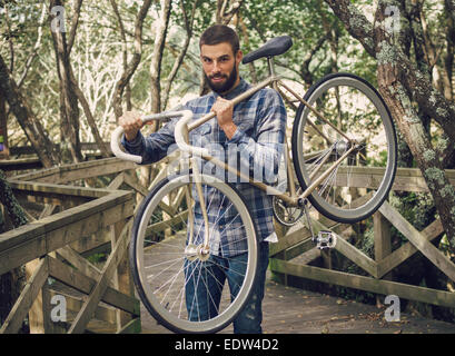 Hipster-Mann mit seinem Fahrrad in einem Park im freien Stockfoto