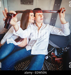 Junge glücklich schwanger Familie viel Spaß und schauen Film Band mit ihren Fotos. Mann und Frau, gekleidet in Jeans und weißen Hemden. Stockfoto