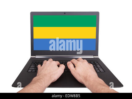 Hände auf Laptop zeigt auf dem Bildschirm die Flagge von Gabun Stockfoto