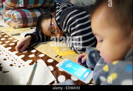 (150110)--TONGGU Grafschaft, 10. Januar 2015 (Xinhua)--Mo Shuangyi (L) und sein jüngerer Bruder tätigen einen Anruf, ihre Eltern, die als Wanderarbeiter in der chinesischen Hauptstadt Peking, in ihrem Haus in Tonggu Grafschaft Yichun, Osten Chinas Jiangxi Provinz, 9. Januar 2015 arbeiten. Nachdem sein Vater an Leukämie im Oktober 2014, Shuangyi, erkrankte 10-jährige Schüler in Tonggu Grafschaft, beschlossen, wiederverwertbare Abfälle zu sammeln und sie für Geld zu verkaufen, um seinen Vater zu retten, der Verzicht auf Behandlung wegen der hohen medizinischen Kosten gedacht. Seine kindlichen Taten umfangreiche Aufmerksamkeit wenn pi Stockfoto