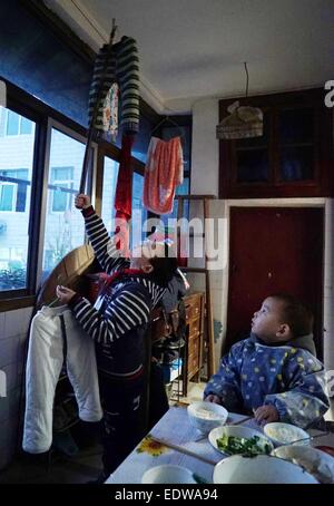 (150110)--TONGGU Grafschaft, 10. Januar 2015 (Xinhua)--Mo Shuangyi (L) hängt neu gewaschen Wäsche zu Hause, als sein jüngerer Bruder blicken Tonggu Grafschaft von Yichun, Osten Chinas Jiangxi Provinz, 9. Januar 2015. Nachdem sein Vater an Leukämie im Oktober 2014, Shuangyi, erkrankte 10-jährige Schüler in Tonggu Grafschaft, beschlossen, wiederverwertbare Abfälle zu sammeln und sie für Geld zu verkaufen, um seinen Vater zu retten, der Verzicht auf Behandlung wegen der hohen medizinischen Kosten gedacht. Seine kindlichen Taten erregte umfangreiche Aufmerksamkeit, wenn Bilder von ihm sammeln Abfälle über das Internet zu verbreiten. Shuangyi fami Stockfoto