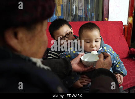 (150110)--hilft TONGGU Grafschaft, 10. Januar 2015 (Xinhua)--Mo Shuangyi seiner Großmutter, seinem jüngeren Bruder in ihrem Haus in Tonggu Grafschaft von Yichun, Osten Chinas Jiangxi Provinz, 9. Januar 2015 zu ernähren. Nachdem sein Vater an Leukämie im Oktober 2014, Shuangyi, erkrankte 10-jährige Schüler in Tonggu Grafschaft, beschlossen, wiederverwertbare Abfälle zu sammeln und sie für Geld zu verkaufen, um seinen Vater zu retten, der Verzicht auf Behandlung wegen der hohen medizinischen Kosten gedacht. Seine kindlichen Taten erregte umfangreiche Aufmerksamkeit, wenn Bilder von ihm sammeln Abfälle über das Internet zu verbreiten. Shuangyi der Familie entgeg Stockfoto