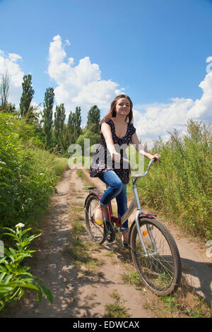 Junges Mädchen im Kleid und Jeans mit einer roten Fahrrad Stockfoto