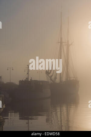 Ein nebeliger Morgen im Hafen von Oslo Norwegen, Segler-Silhouette orange gefärbt Dunst Stockfoto