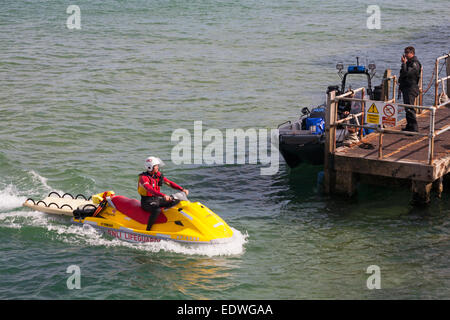 RNLI Rettungsschwimmer Jetski mit Bademeister Annäherung an Pier wo sind Polizisten auf Patrouille in Bournemouth im August binden Stockfoto