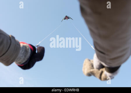 Lenkdrachen fliegen mit Hände im Winter vor einem blauen Himmel, wie von unten gesehen Stockfoto