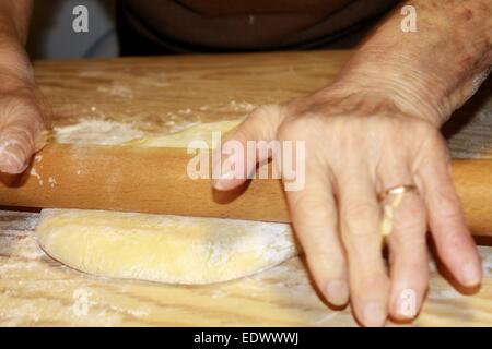 Teig wird auf einem Holzbrett abgeflacht Stockfoto