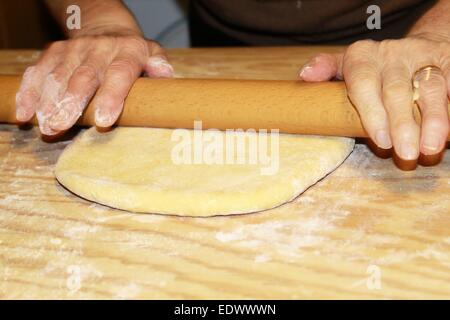 Teig wird auf einem Holzbrett abgeflacht Stockfoto