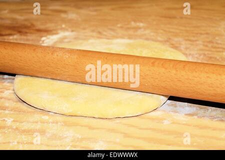 Teig wird auf einem Holzbrett abgeflacht Stockfoto