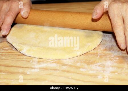 Teig wird auf einem Holzbrett abgeflacht Stockfoto