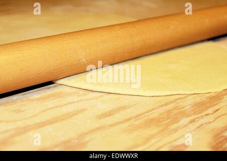 Teig wird auf einem Holzbrett abgeflacht Stockfoto