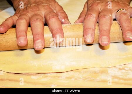 Teig wird auf einem Holzbrett abgeflacht Stockfoto