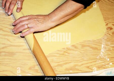 Teig wird auf einem Holzbrett abgeflacht Stockfoto