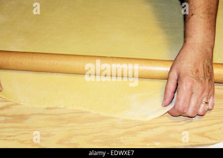 Teig wird auf einem Holzbrett abgeflacht Stockfoto