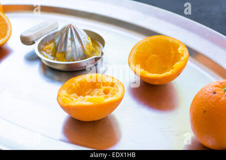 frisch gepressten Orangen auf einem silbernen Tablett mit Silber Metall Hand Saftpresse. Stockfoto