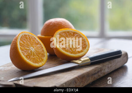 Schneiden Sie Orangen auf Holz Holzsteg auf Tisch Garten Hintergrund Fenster gerahmt Stockfoto