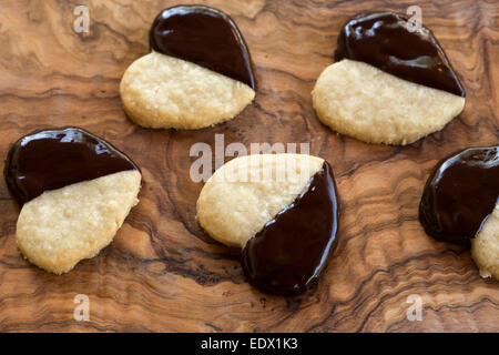 hausgemachte Schokolade getaucht Herz Kekse oder Cookies auf Oliven Holz Brett Stockfoto