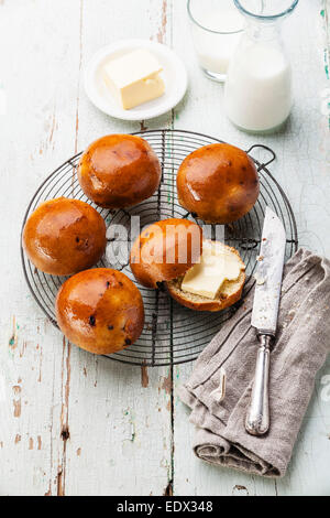 Hausgemachte Brötchen mit Rosinen auf Kuchengitter abkühlen auf blauem Hintergrund aus Holz Stockfoto