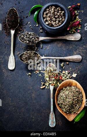 Tee-Komposition mit verschiedenen Arten von Tee und alte Löffel auf dunklem Hintergrund Stockfoto