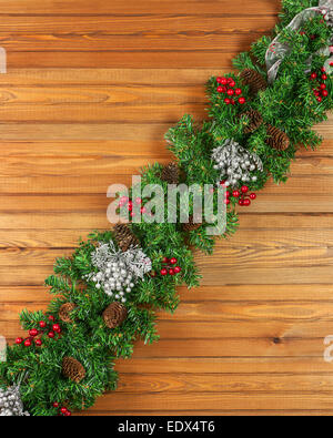 Girlanden Sie mit Weihnachtsschmuck und Tannenzapfen auf alten hölzernen Hintergrund. Stockfoto