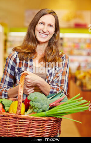 Attraktive ältere Frau shopping Korb voll mit frischem Gemüse Stockfoto