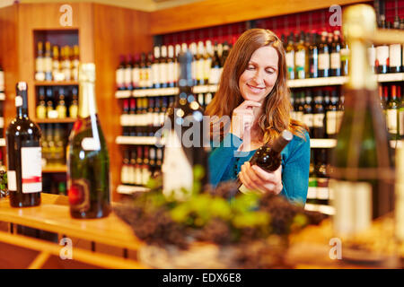 Attraktive Frau mit Flasche Rotwein im Bioladen lächelnd Stockfoto