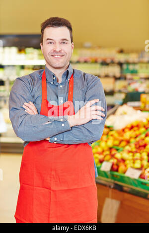 Lächelnde Verkäufer steht mit seinen Armen überquerte in einem Supermarkt Stockfoto
