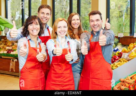 Glückliche Mitarbeiter-Team in einem Supermarkt die Daumen hochhalten Stockfoto