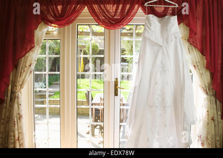 weiße Brautkleid von einer Gardinenstange hängen Stockfoto