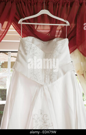 weiße Brautkleid von einer Gardinenstange hängen Stockfoto