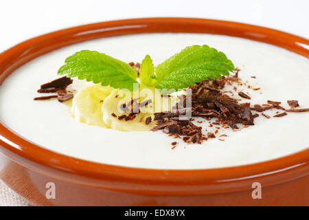 Schüssel mit glatten Milchbrei mit in Scheiben geschnittenen Bananen und geriebener Schokolade Stockfoto