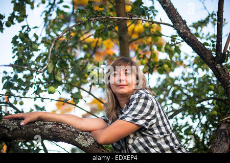 Junge Frau auf einem Baum in die Apfelplantage. Stockfoto