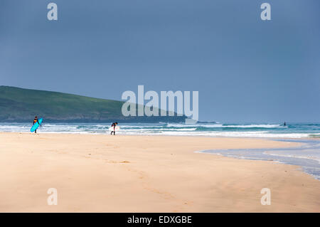 Surfer, die ihren Weg zum Meer, mit ihren Brettern Crantock Beach in der Nähe von Newquay, Cornwall. Stockfoto