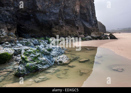 Felsenpool und hohen Klippen am Strand von Perranporth in Cornwall an einem bewölkten Tag. Stockfoto