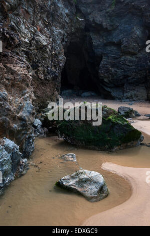 Interessante Geologie in den Felsen am Strand von Perranporth in Cornwall. Ein Felsenpool und dunkle Höhle. Stockfoto