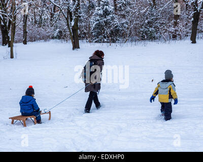 Mutter zieht Kind auf Schlitten im Winter im verschneiten öffentlichen Park, Humbolthain Volkspark im Brunnenviertel, Berlin Stockfoto