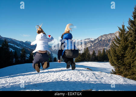 zwei Teenager blonden Haaren in die Luft springen auf einen Skiurlaub in der Schweiz Stockfoto