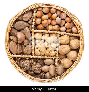 eine Vielzahl von Nüssen (Walnuss, Pekannuss, Haselnuss, Brasilianer und Mandel) in einem Weidenkorb, isoliert auf weiss Stockfoto