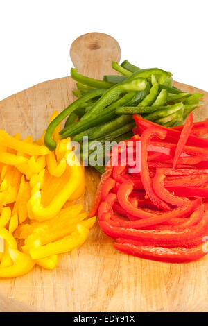 In Scheiben geschnittene rote, grüne und gelbe Paprika auf einem hölzernen Schneidebrett Stockfoto