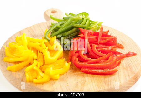 In Scheiben geschnittene rote, grüne und gelbe Paprika auf einem hölzernen Schneidebrett Stockfoto