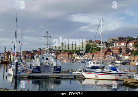 Sonnige Sommer Blick auf Yachten & Boote in der Marina mit St Mary's Church & Abtei günstig auf Klippe hinaus - Whitby Harbour, Yorkshire, England, UK. Stockfoto