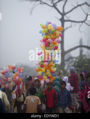 Dhaka, Bangladesch. 11. Januar 2015. Bangladeshi junge trägt Ballons zum Verkauf, wie er muslimischen Gläubigen gehen Uhren, um das letzte Gebet der dreitägigen islamischen Gemeinde an den Ufern des Flusses Turag in Tongi, 20 Kilometer (13 Meilen) nördlich der Hauptstadt Dhaka zu besuchen. Hunderttausende von Muslimen besuchte die jährliche dreitägige Veranstaltung, die eine der weltweit größten religiösen Versammlungen gehalten seit 1960, islamische Lehren wieder zu beleben. Er meidet Politik und fordert für den Frieden. © Zakir Hossain Chowdhury/ZUMA Draht/Alamy Live-Nachrichten Stockfoto