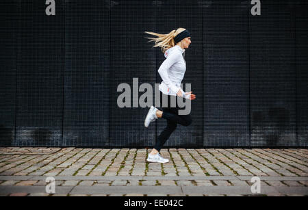 Seitenansicht der sportliche junge Frau auf Bürgersteig morgen ausgeführt. Bewusste Gesundheitskonzept mit Textfreiraum. Stockfoto